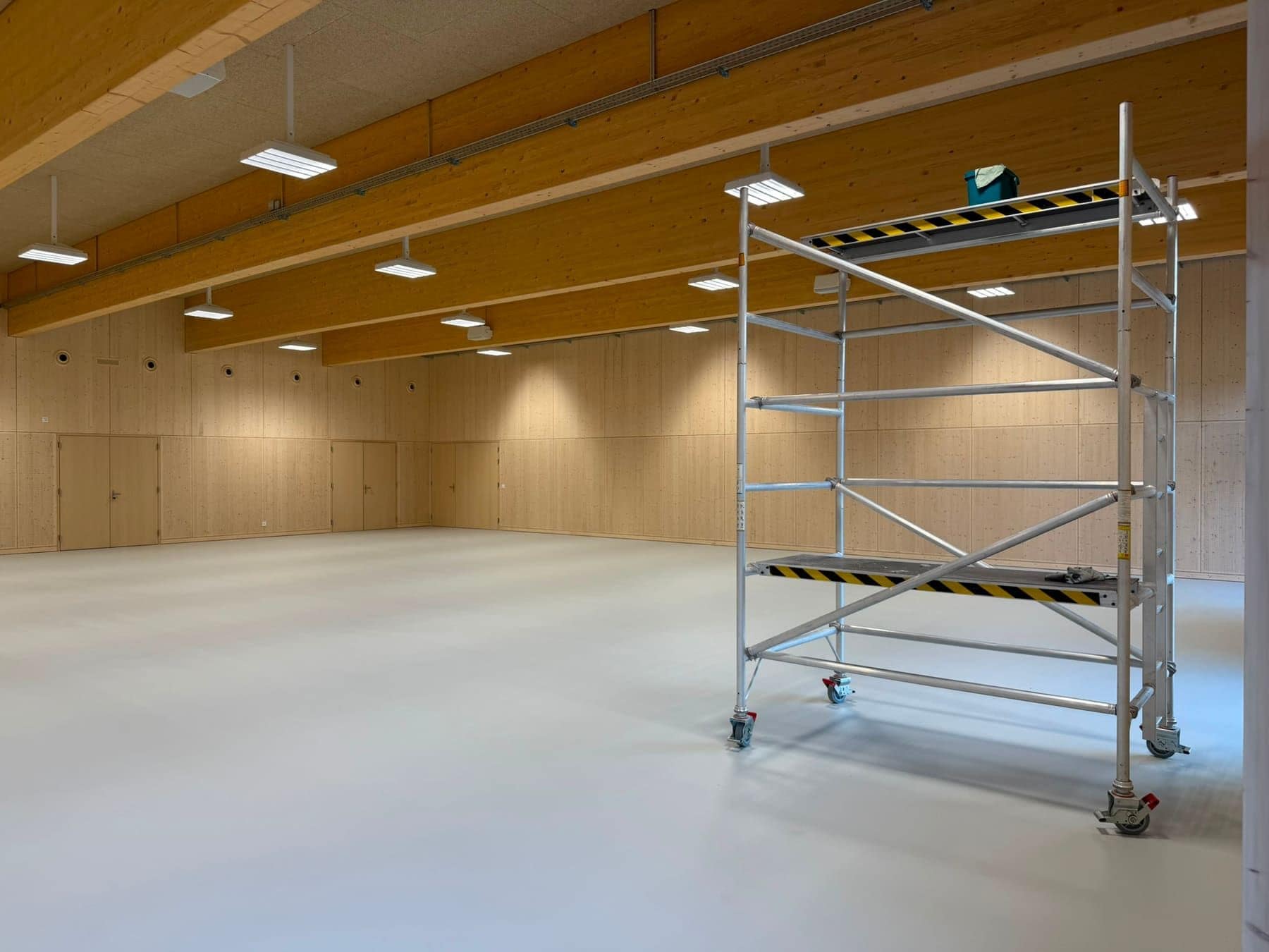 Saal mit Holzdecke während der Bauendreinigung, ein Rollgerüst steht im Raum